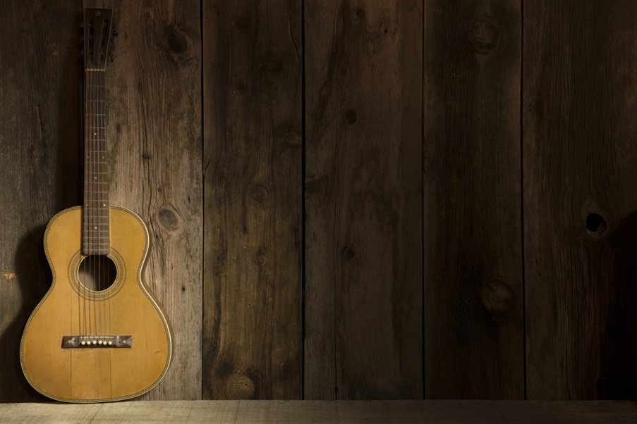 an acoustic guitar sitting against a wall.