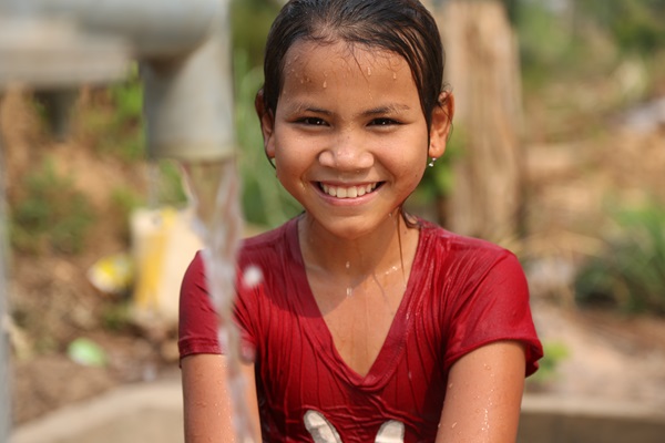 Smiling girl at a water pump