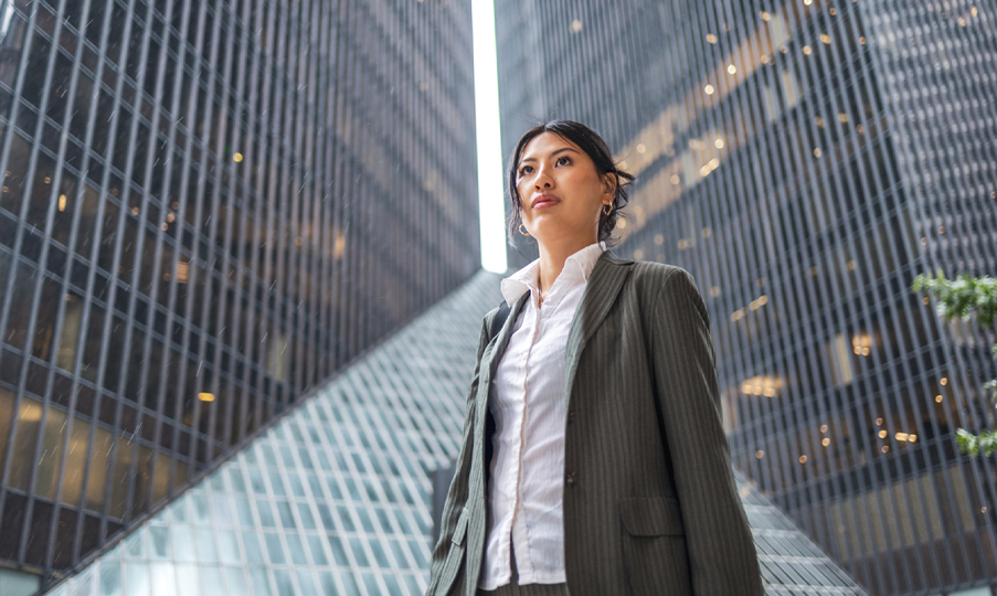 Woman in work wear stands in front of mirrored buildings