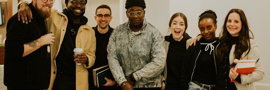 Group of 7 young adults, men and women, all smiling and laughing