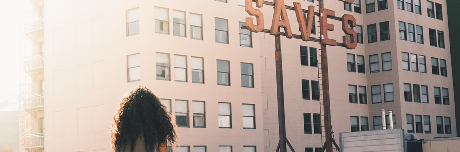 Girl sits on a rooftop, facing a large sign that reads JESUS SAVES