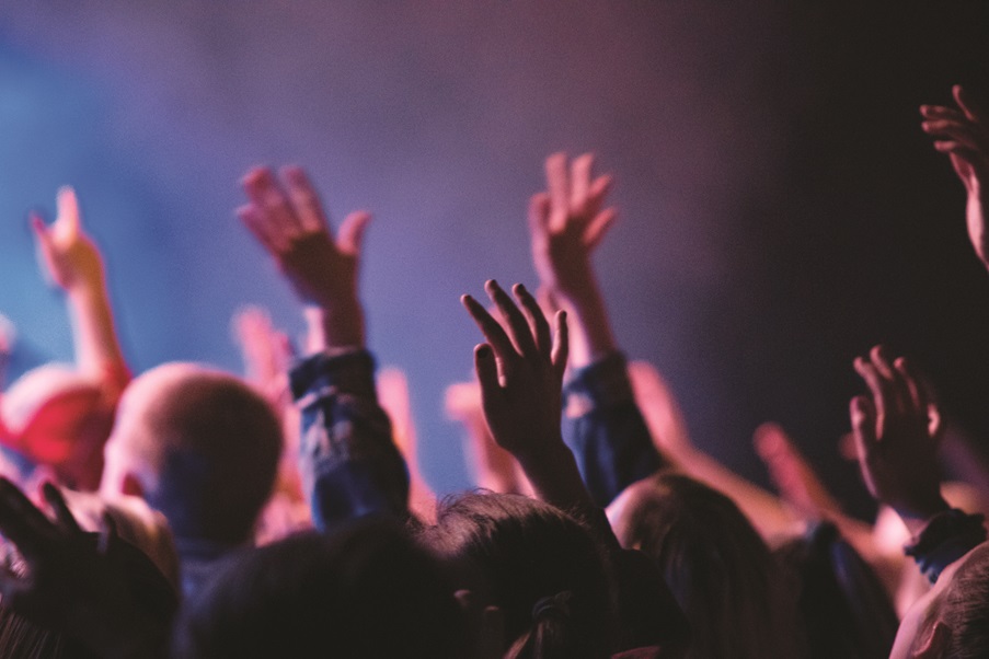 Image of a crowd of people in a state of worship, with hands raised