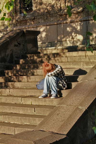 girl sitting on the stairs with her head in her hands