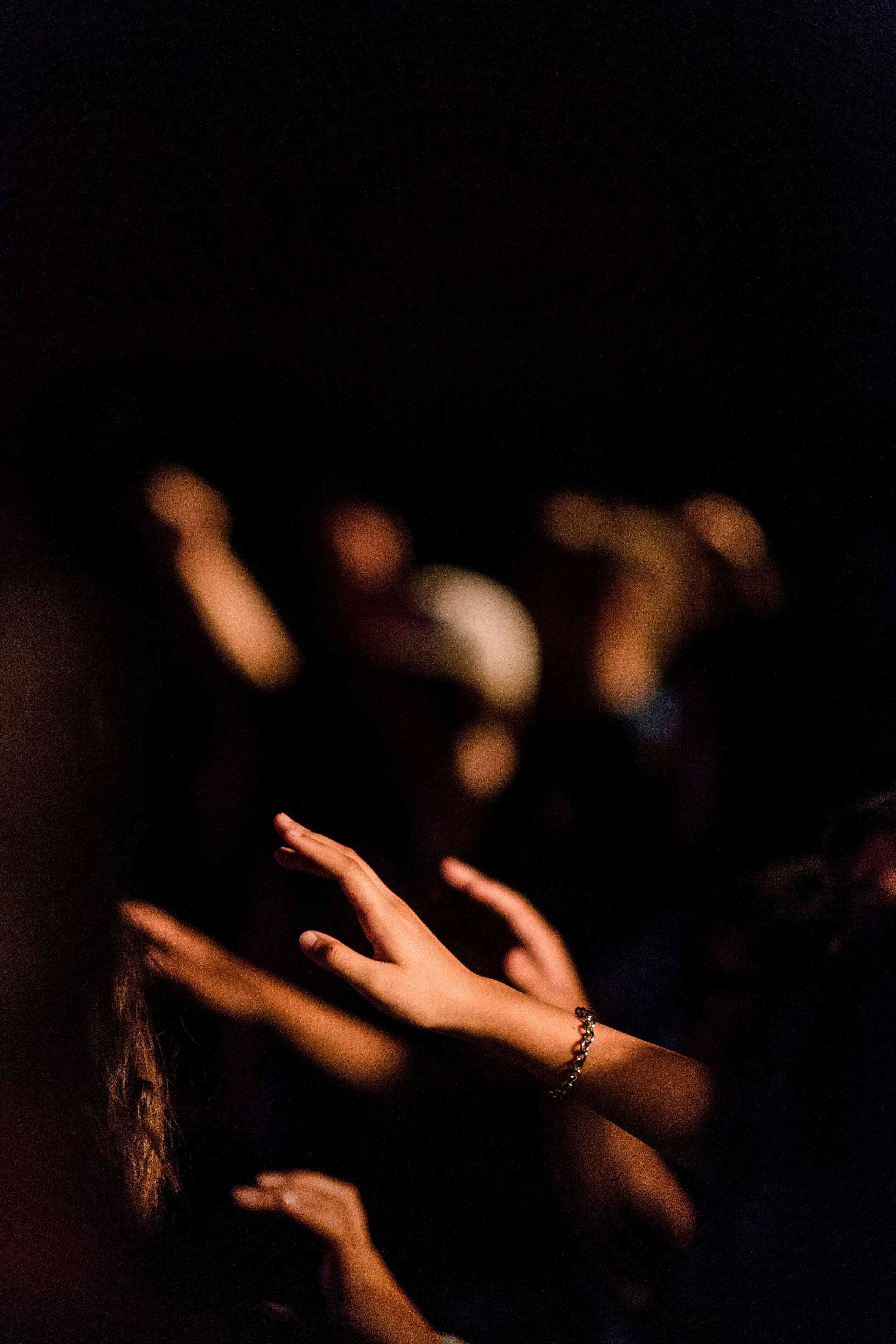 Hands lifted in a dark room during a church worship service.