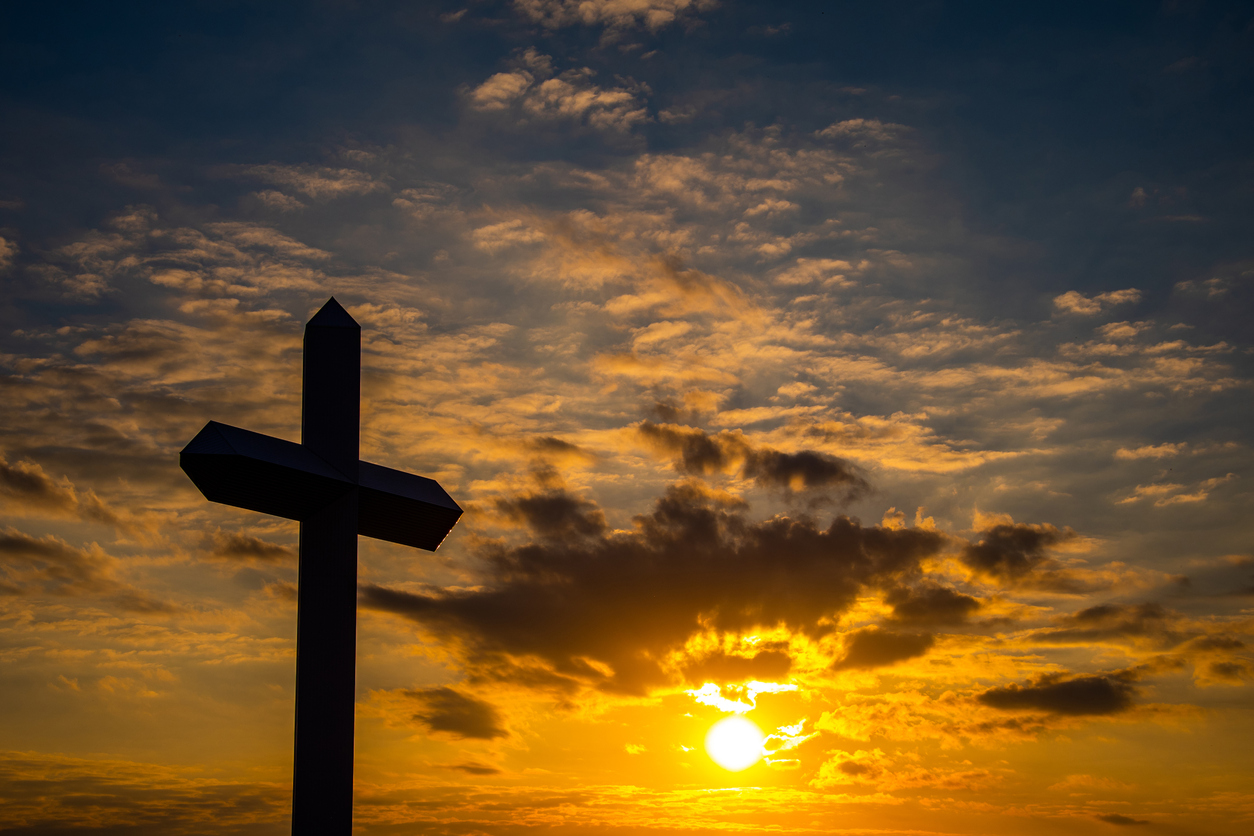A large Christian cross at sunset with brilliant cloudy sky.